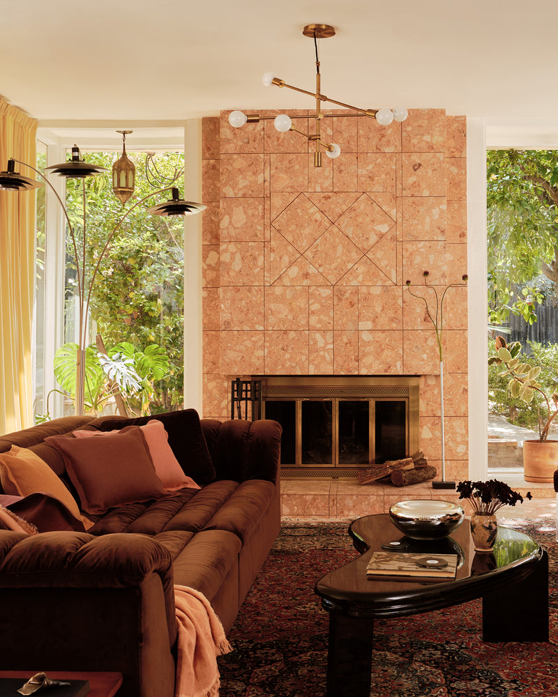 Living room with a brown sectional sofa covered with 100% French flax linen soft furnishings in terracotta, pink clay and cacao; plus a coffee table, and stone fireplace.