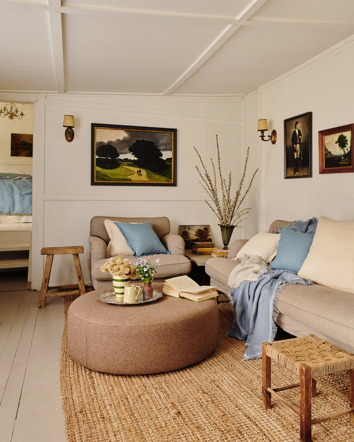 Living room with beige sofa, ottoman, and decorative cushions and throws in lagoon and cream.