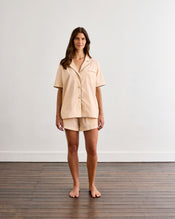 A person wearing Bed Threads' Vanilla & Espresso Piped Short Sleep Set, with hands partially in the side pockets, is shown from mid-torso to mid-thigh against a plain background. - view