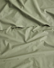 A close-up of organic cotton olive green sheets with soft folds and a horizontal seam, filling the entire frame. - view
