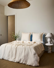 Two Crème & Coast 100% French Flax Linen Swirl European Pillowcases by Bed Threads rest against a light blue headboard, paired with a light beige sheet and soft natural lighting for an inviting look. - view