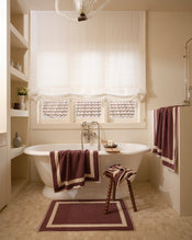 Neutral bathroom with freestanding bath tub and cotton terry towels in a cacao colour with creme border. - view