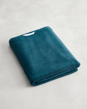 Aegean 100% Cotton Terry Bath Sheet by Bed Threads in plush teal, neatly folded with a small white label, sits on a light gray textured surface—ideal for those seeking quick-drying cotton bath sheets. - view