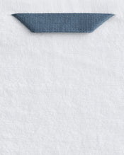 A close-up of the Bed Threads Crisp White 100% Cotton Terry Bath Sheet Bundle, showing a dark blue fabric loop neatly sewn onto the top edge for easy hanging. - view