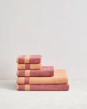 The Bed Threads Terracotta & Pink Clay Two-Toned 100% Cotton Terry Bath Sheet Bundle features four luxury bath sheets stacked by size, adding spa-like elegance to any bathroom décor. - view