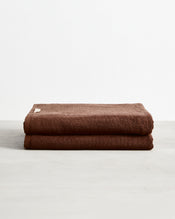 Two Espresso 100% Cotton Terry Bath Sheets by Bed Threads, neatly folded and stacked on a light gray surface against a plain white background. Set of two. - view