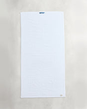 A set of two Bed Threads Crisp White 100% Cotton Terry Bath Towels is laid flat on a light surface, featuring a small blue loop and beige tag, highlighting their plushness and high absorbency. - view
