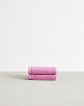 A set of two Bed Threads Bubblegum 100% Cotton Terry Face Washers, soft and gentle on skin, are neatly folded and displayed on a light gray surface with a plain white background. - view