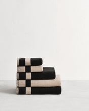 Stack of cotton terry towels in reversible colours oatmeal and charcoal. - view