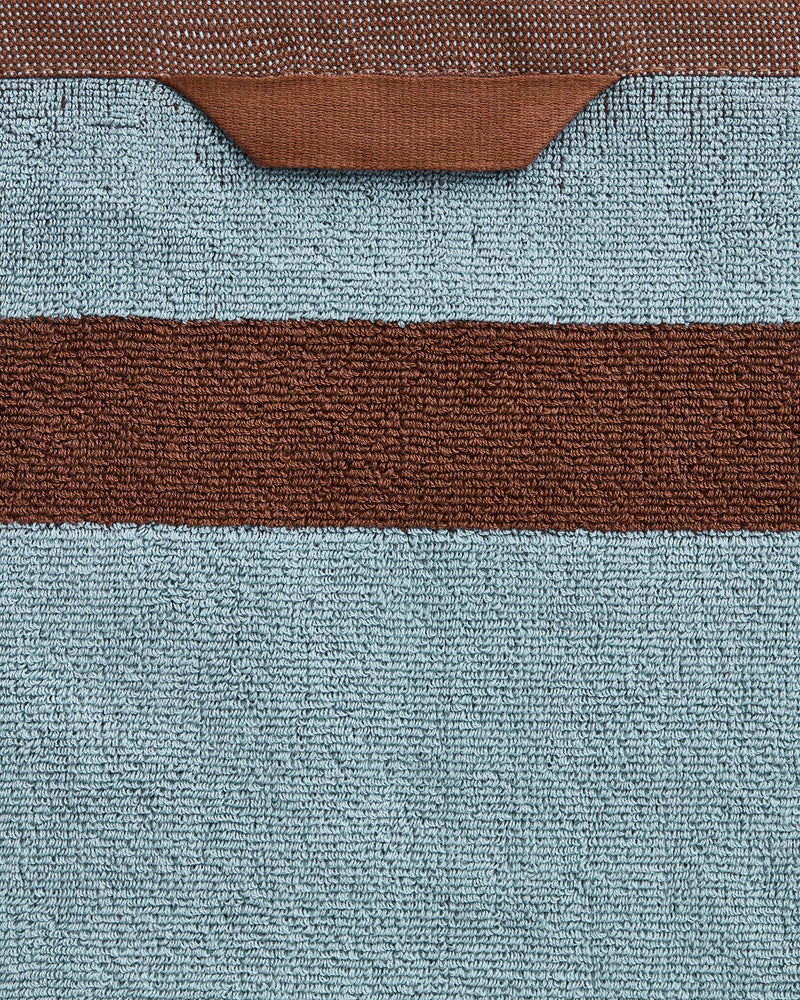 A close-up of Bed Threads’ Cacao & Lagoon Two-Toned 100% Cotton Terry Hand Towels (Set of Two), featuring plush 650GSM light blue cotton with a horizontal brown stripe and a brown trim along the top edge.