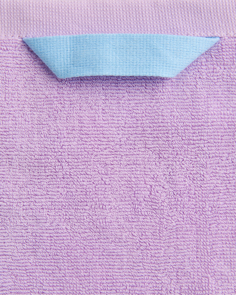 A close-up of the Bed Threads Violet 100% Cotton Terry Hand Towel, featuring a plush 650GSM texture and a light blue quick-drying hanging loop sewn onto the top edge, folded outward for easy use.