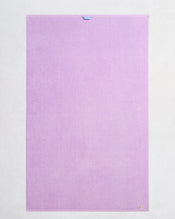 The Bed Threads Violet 100% Cotton Terry Bath Sheet, shown flat on a light background, features a plush quick-drying texture, a small top-center loop, and a beige tag at the lower right corner. - view