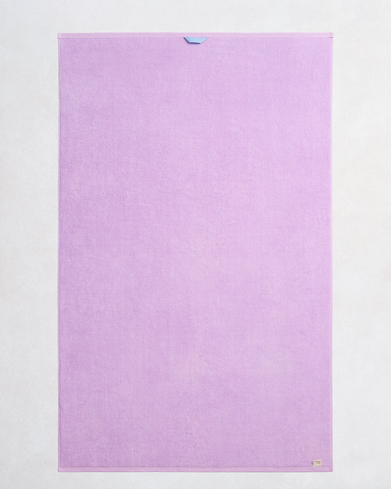 The Bed Threads Violet 100% Cotton Terry Bath Sheet, shown flat on a light background, features a plush quick-drying texture, a small top-center loop, and a beige tag at the lower right corner.